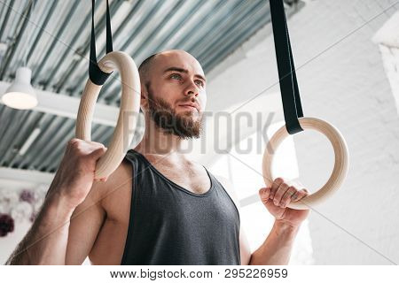 Strong Bearded Athlete Holding Crosstraining Rings At Cross Hall. Muscular Man Holding Gymnastic Rin