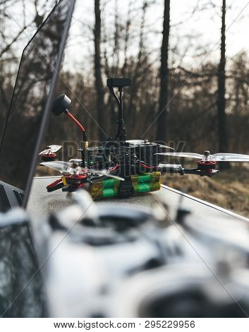 Fpv Drone Lies On The Table Near The Laptop And Control Panel. The Pilot Sets Up His Racing Drone Be