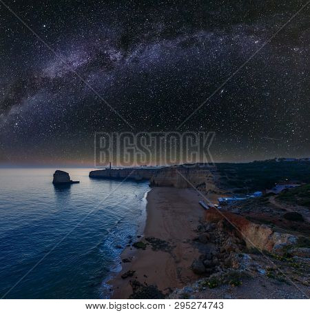 Sea Coast Night View With Lighthouse Of Ponta Do Altar And Starry Milky Way In Sky. West View Over P