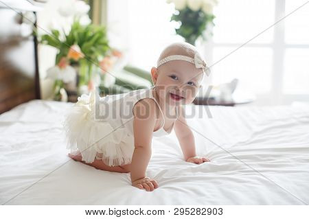 A Small Child Of 5 Months Is Having Fun Alone, Crawling On The Bed.baby Girl Crawling On Bed And Lau
