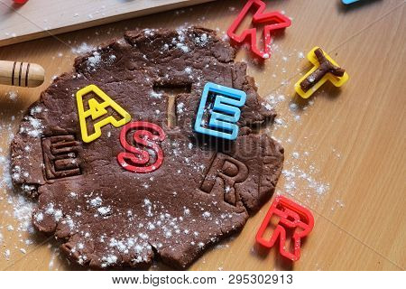 Cut Cookies From Raw Chocolate Dough On A Wooden Table With Colorful Letters. Cooking Traditional Ea