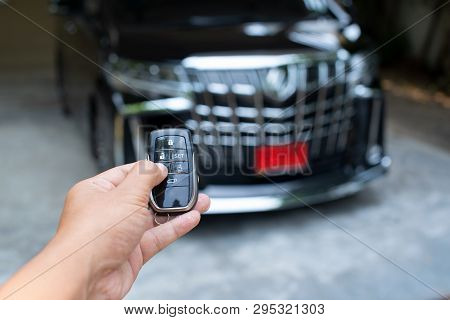 Men's Hand Holding Car Key Ready To Start A New Car With Blurred Black Car Background.hand Hold Key 