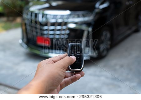 Men's Hand Holding Car Key Ready To Start A New Car With Blurred Black Car Background.hand Hold Key 