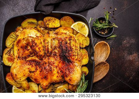 Fried Whole Tabaka Chicken With Potatoes In A Grill Pan, Top View, Dark Background.