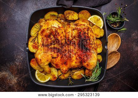 Fried Whole Tabaka Chicken With Potatoes In A Grill Pan, Top View, Dark Background.