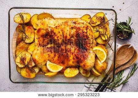 Roasted Whole Tabaka Chicken With Potatoes In A Glass Oven Dish, Top View, White Background.