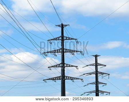 High Voltage Power Line Supports With Electrical Wires On Background Of Blue Sky With White Clouds. 