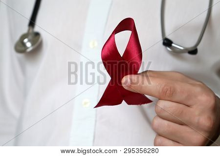 Doctor Holding Red Ribbon. Aids, Cancer And Vasculitis Awareness, Oncology And Health Care Concept