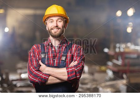 Young cheerful worker of large contemporary machinebuilding factory looking at you inside workshop