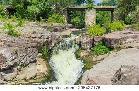 Small Waterfall On River Flowing From Under A Stone Bridge