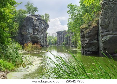 Plain River In Canyon With Overhanging Rocks On Two Banks