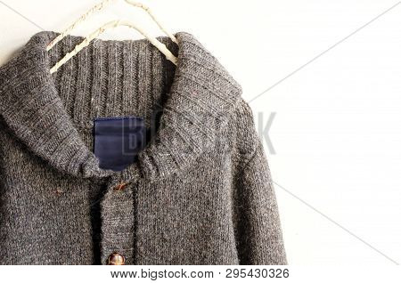 A Thick Knitted Cardigan In Brown Hanging On Clothes Hanger On White Background.close Up.
