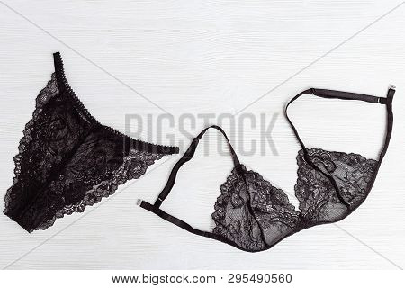 Fashionable Female Underwear On Wooden Background. Top View On Black Guipure Lingerie On White Surfa