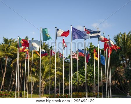 A Set Of International Flags Blowing In The Breeze And In A Tropical Setting On Flag Poles With A Cl