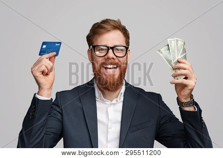 Handsome Irish Man With Ginger Beard Smiling And Offering To Choose Between Bank Card And Banknotes 