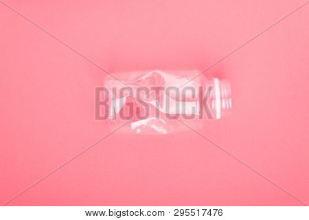 Squashed plastic bottle on coral pink background. Plastic utilisation concept. Ecological problem, global environment.