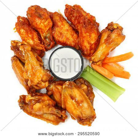 Spicy Chicken Wings with carrots, celery and ranch over white.