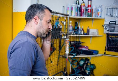 Car Mechanic Having A Phone Call With A Customer About Some Car Issue.