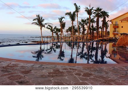 Cabo San Lucas Resort Pool With Palm Trees, Glassy Reflections And Ocean In The Background