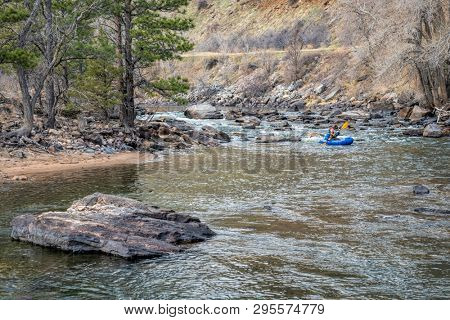 paddler in an inflatable packraft on a mountain river in early spring - Poudre River above Fort Collins, Colorado