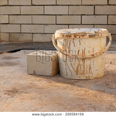 Bucket And Brick Near A Wall In Sunny Day