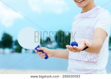 Young Smiling Woman In Light Clothes Is Holding White Racket And Ball In Her Hands. Cheerful Female 