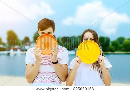 Young Smiling Woman In Light Clothes Is Holding White Racket And Ball In Her Hands. Cheerful Female 