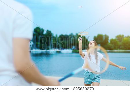 Young Smiling Woman In Light Clothes Is Holding White Racket And Ball In Her Hands. Cheerful Female 
