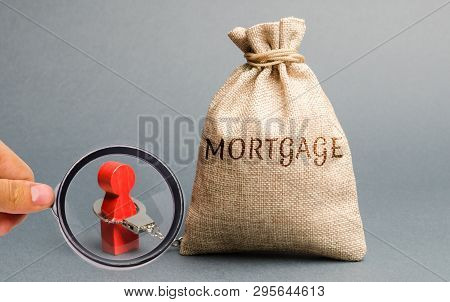 The Figure Of A Man Is Handcuffed To A Money Bag With The Word Mortgage. Impossibility Of Paying Int