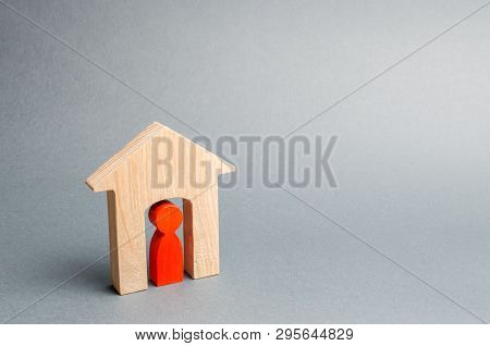Miniature Wooden House With A Tenant Inside. The Concept Of Renting A House Or Apartment. Affordable