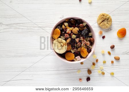 Dried Fruits And Nuts In A Pink Bowl Over White Wooden Surface, Top View. Overhead, From Above, Flat