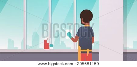 Man In Gloves And Apron Cleaning Windows With Rag Cleaner Spray Rear View African American Guy Doing