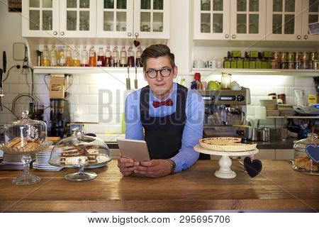 Young Businessman Standing In His Cafe And Waiting For Guest While Using Digital Tablet