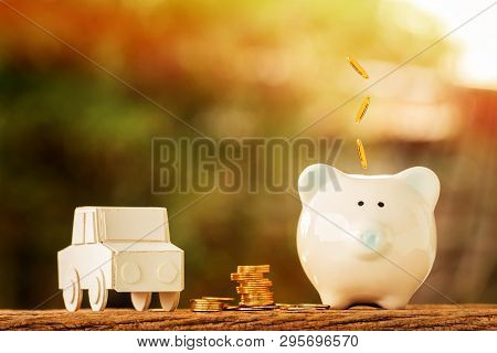 Car Model And Piggy Bank And Drop Gold Coin On The Top Put On The Wood On Nature Bokeh In The Public