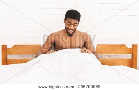 Hello There. Smiling African American Guy Looking At His Strong Morning Erection Under Sheets In Bed