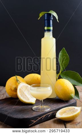 Lemoncello In A Bottle On A Black Background, Traditional Italian Liqueur From Lemons. Alcohol Yello