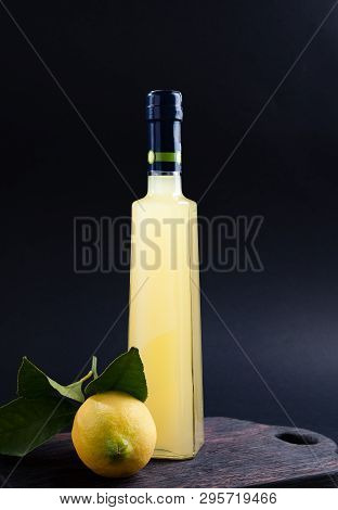 Lemoncello In A Bottle On A Black Background, Traditional Italian Liqueur From Lemons. Alcohol Yello