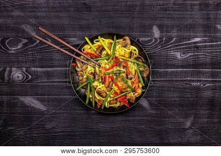 Appetizing Stir Fried Noodles With Garlic Sprouts, Mushrooms, Red Pepper And Chicken Meat On A Black