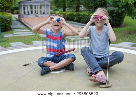 Happy Brother And Sister Playing Mini Golf