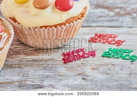 Muffin Coated With Chocolate And Chocolate Lentils On A Wooden Surface With Decoration Showing The W