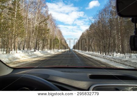 View Of The Road Through The Windshield. Snow On The Sidelines. Wet Asphalt Road. Blue Sky With Clou