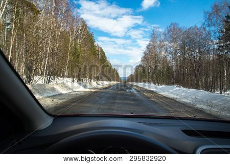 View Of The Road Through The Windshield. Snow On The Sidelines. Wet Asphalt Road. Blue Sky With Clou