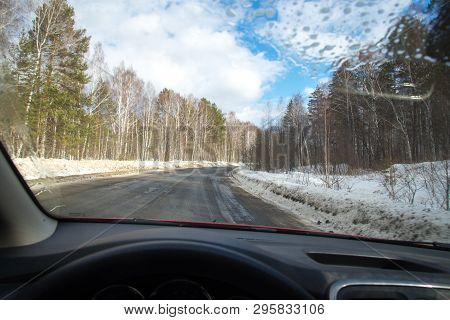 View Of The Road Through The Windshield. Snow On The Sidelines. Wet Asphalt Road. Blue Sky With Clou