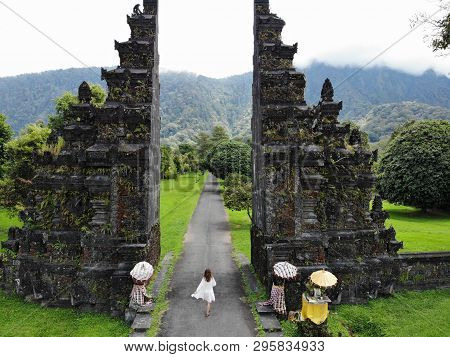 Tourist Woman Walking Through The Balinese Gate Candi Bentar. Vacation On Bali.