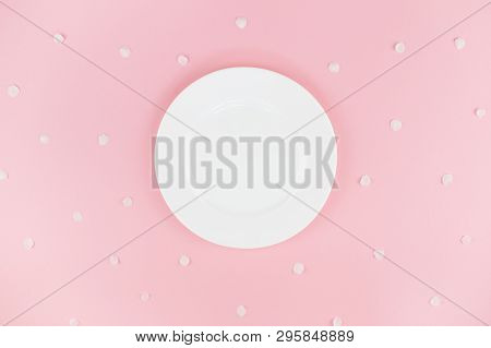 White Plate On Pink Background With White Petals. Festive Background For Your Design. Flat Lay Style