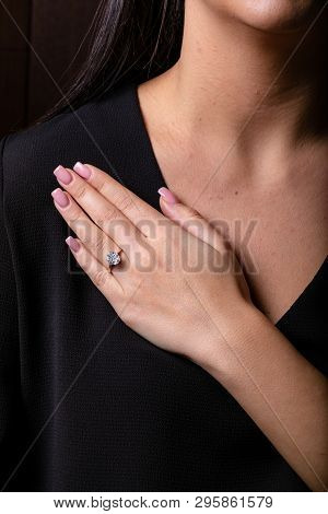 Womens Silver Ring With A Diamonds In The Middle On Finger, On A Black Background.