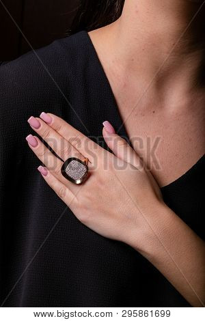 Womens Gold Ring With A Diamonds In The Middle On Finger, On A Black Background.