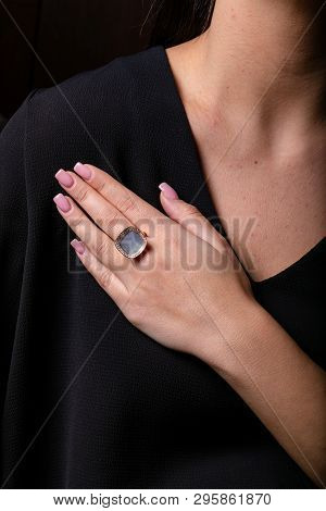 Womens Gold Ring With A Diamonds Fringe, With Stones In The Middle On Finger, On A Black Background.