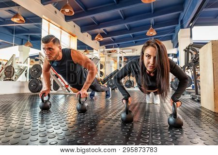 Attractive Young Woman And Man Do Plank Exercise In Gym