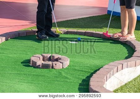 A Man Prepares To Hit A Ball During Mini Golf Game